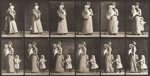 Walking, Carrying a Child, Turning Around; Another Child Holding onto the Woman's Dress