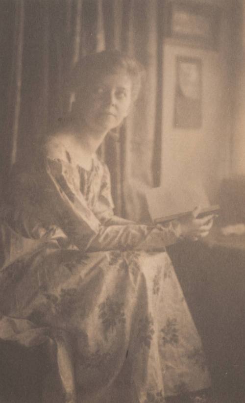 Woman in Flowered Dress, Seated Holding a Book