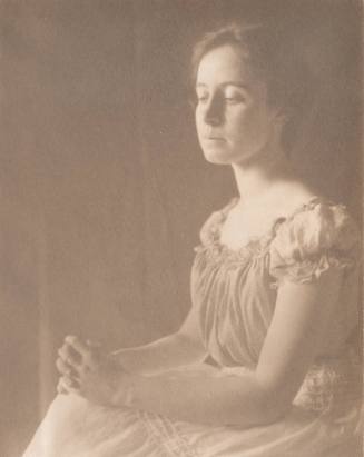 Woman in Short Sleeved Blouse With Hands Clasped on Knees